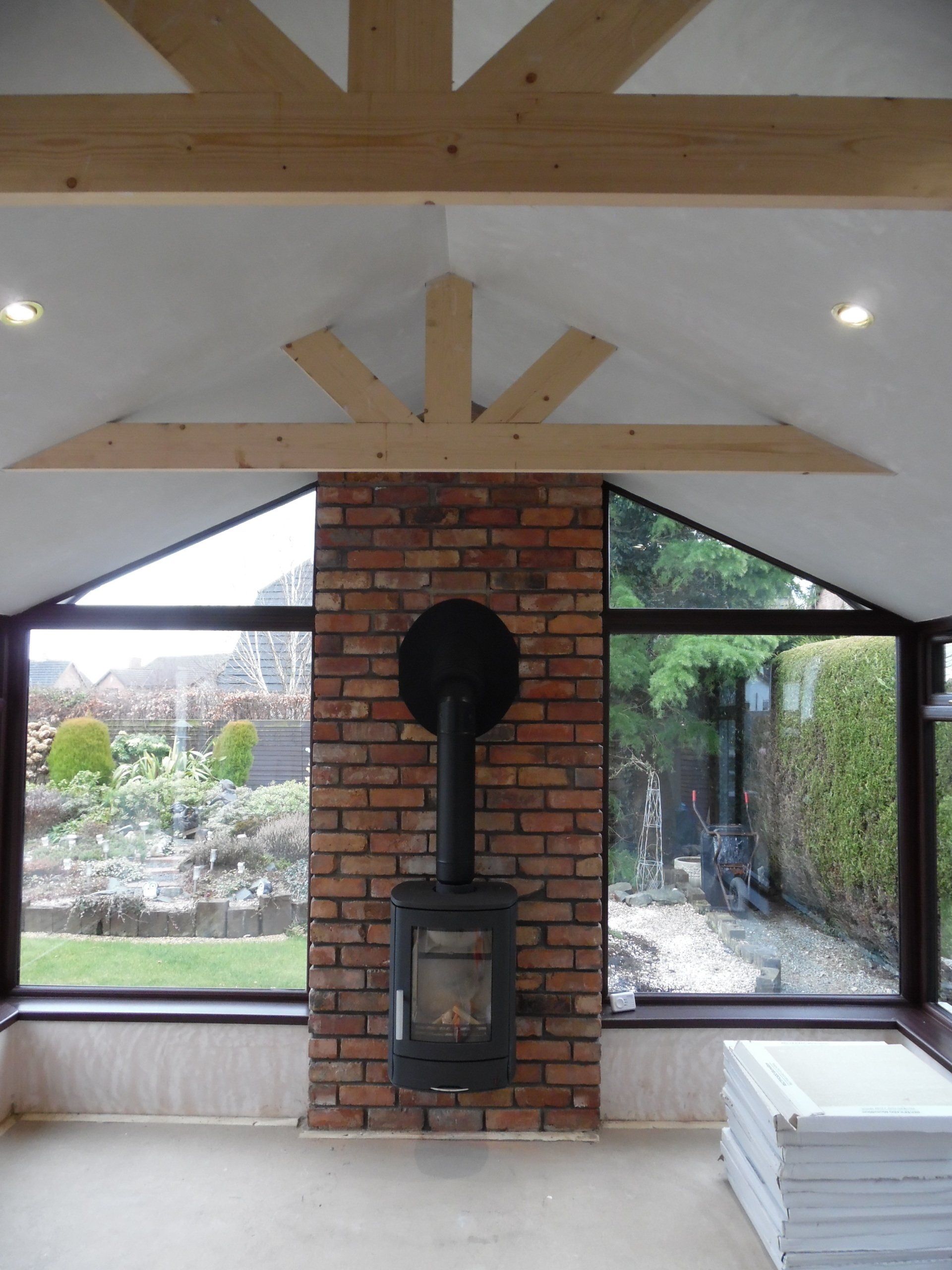 A room with a brick fireplace and lots of windows