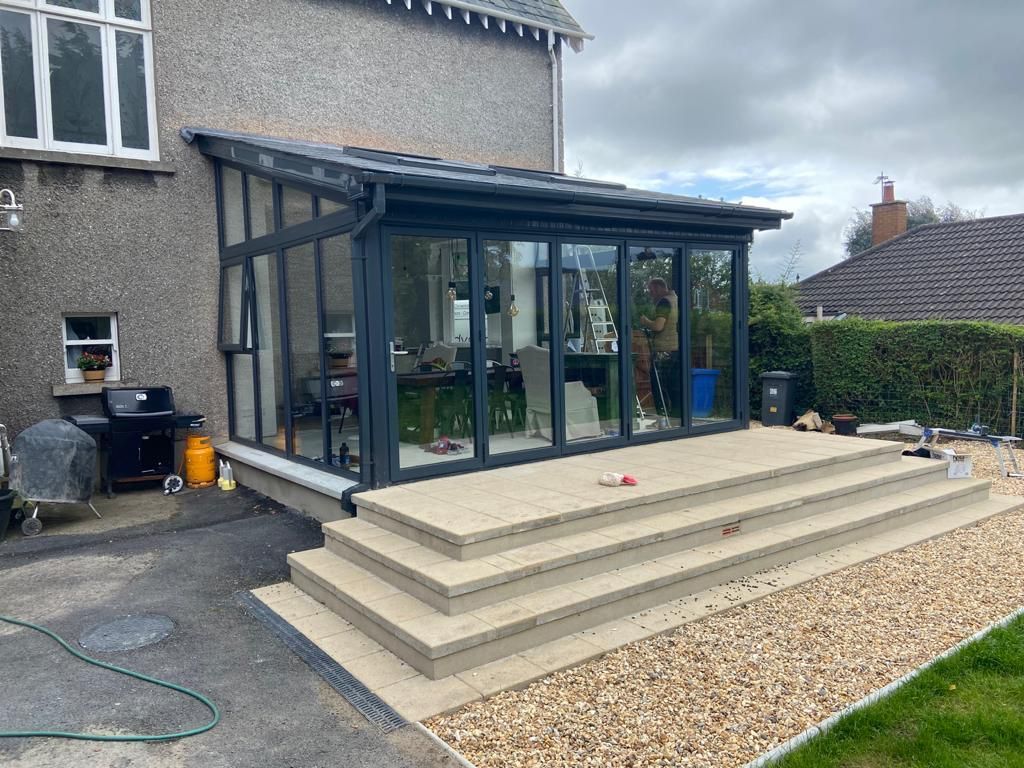 A conservatory with stairs leading up to it is being built in the backyard of a house.