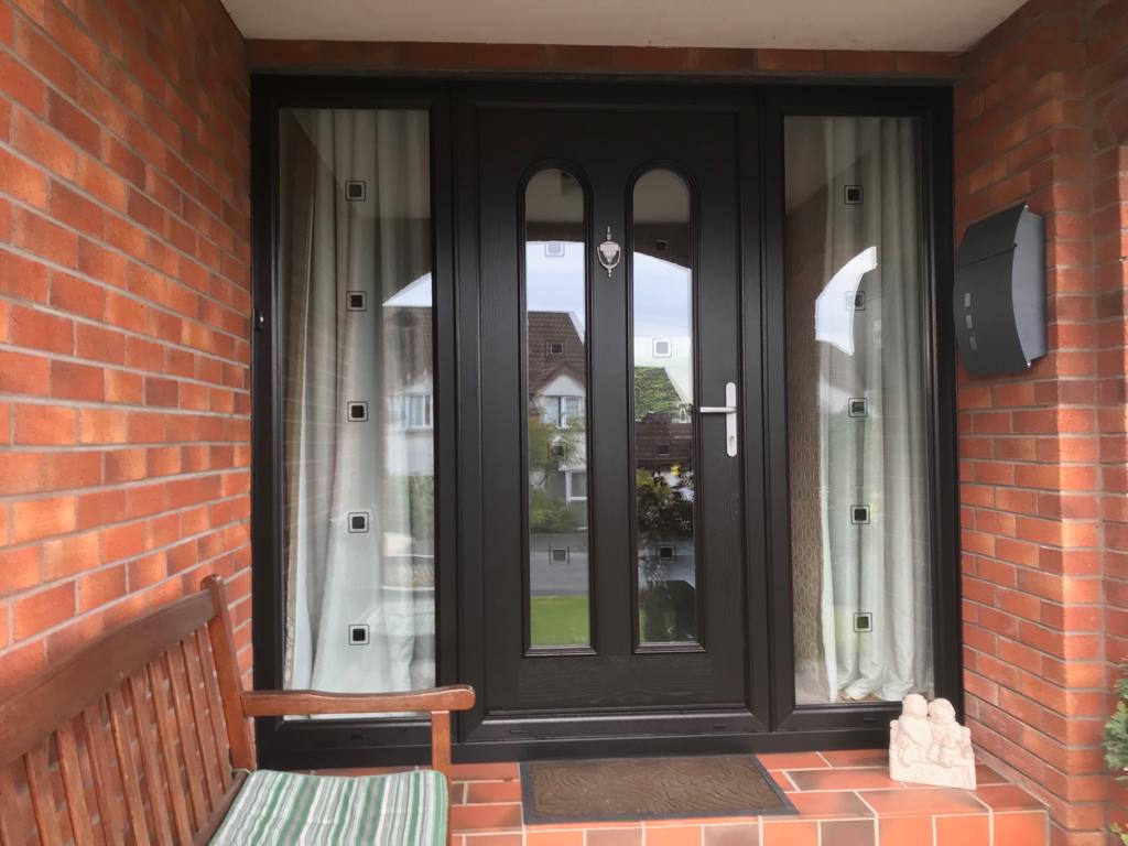 There is a bench in front of the door of a brick house.