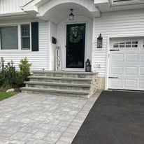 A white house with a white garage door and steps leading to the front door.