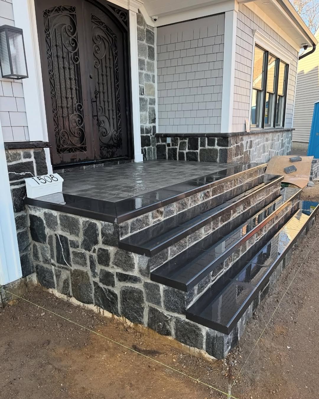 A stone porch with stairs leading up to the front door of a house.