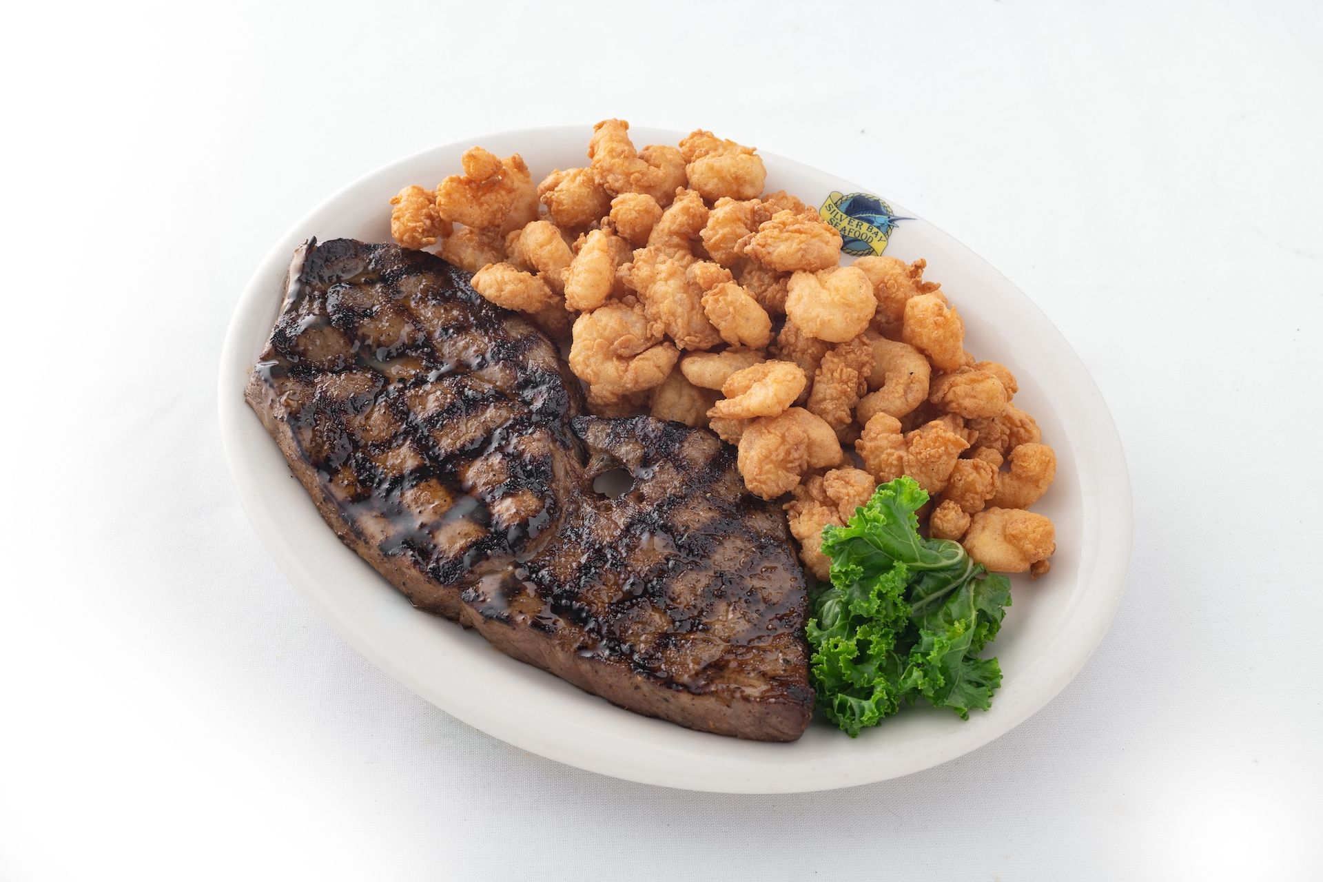 A white plate topped with a steak and shrimp.