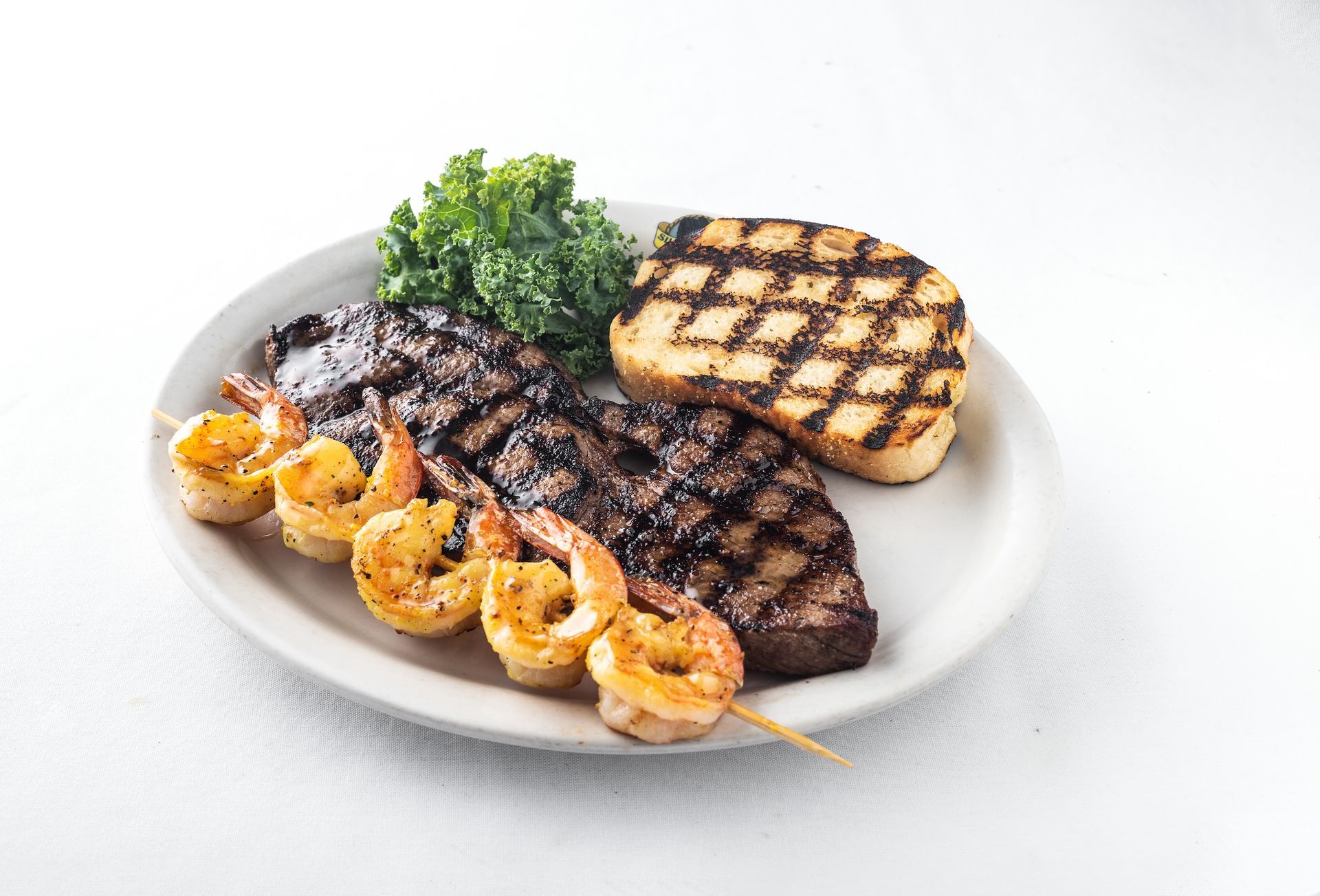 A white plate topped with a steak and broccoli next to a bowl of broccoli.