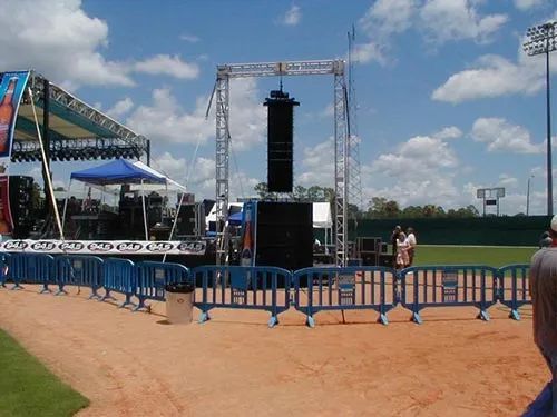 A baseball field with a fence and a stage in the background