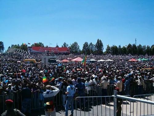 A large crowd of people are gathered in front of a fence