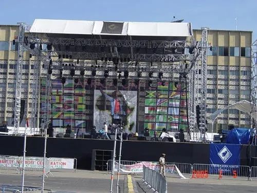 A large stage in front of a building with flags on it