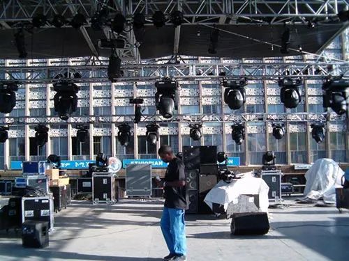 A man is standing in front of a stage with a lot of lights on it