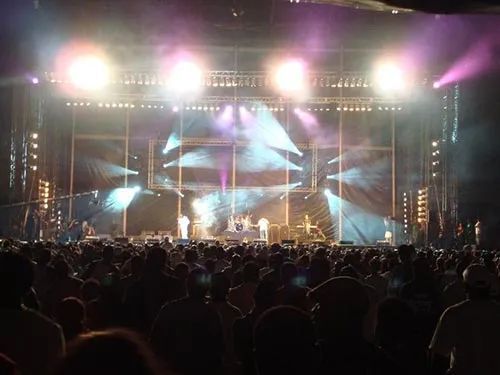 A crowd of people are watching a band on stage at a concert.