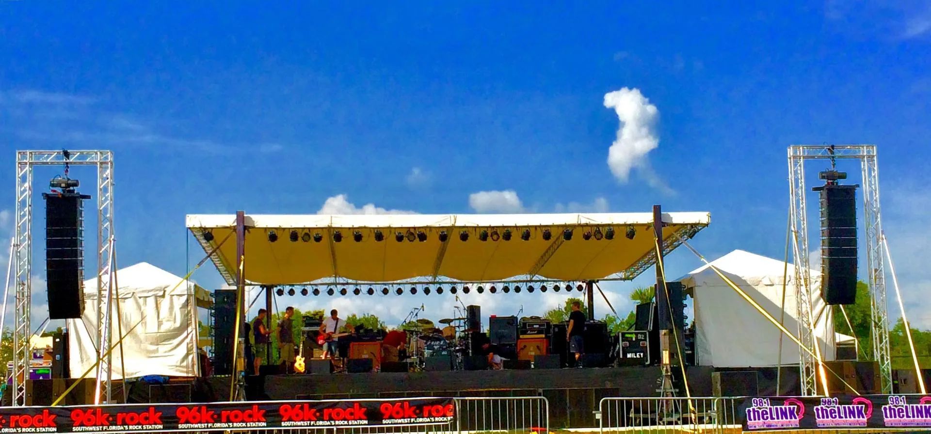 A band is playing on a stage with a blue sky in the background
