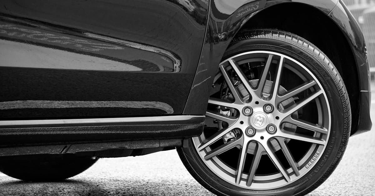 A black and white photo of a car 's wheel and tire.