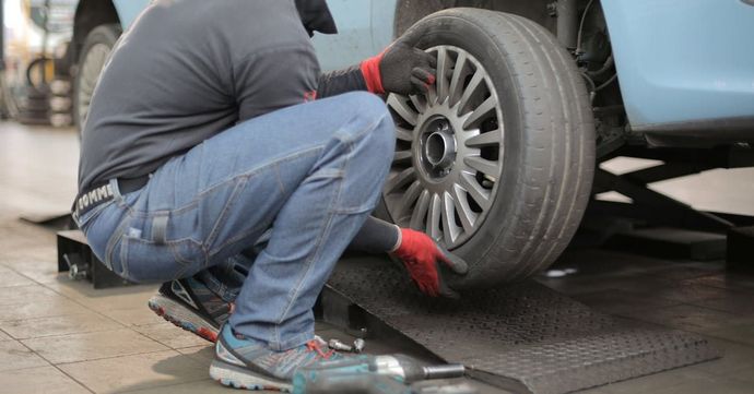 A man is changing a tire on a car in a garage.