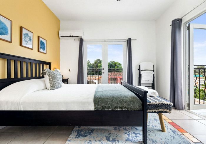 Bedroom with black bed, yellow accent wall, and balcony doors.