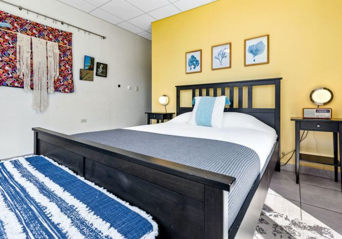 Bedroom with a black bed, yellow accent wall, and blue decor.