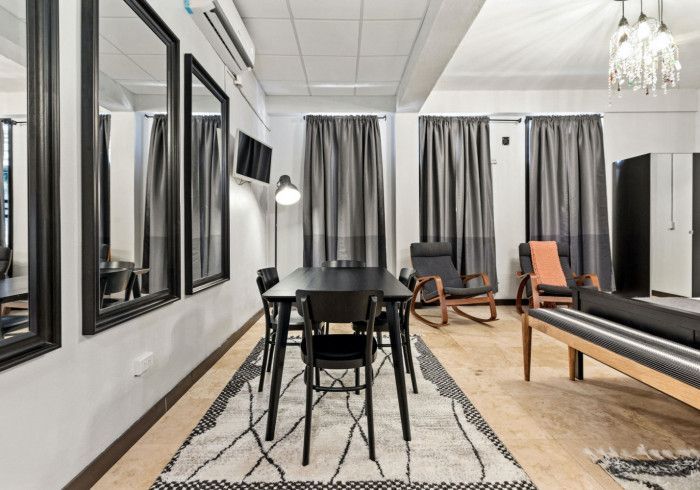 Modern dining area with black table, chairs, mirrors, gray curtains, and rug.