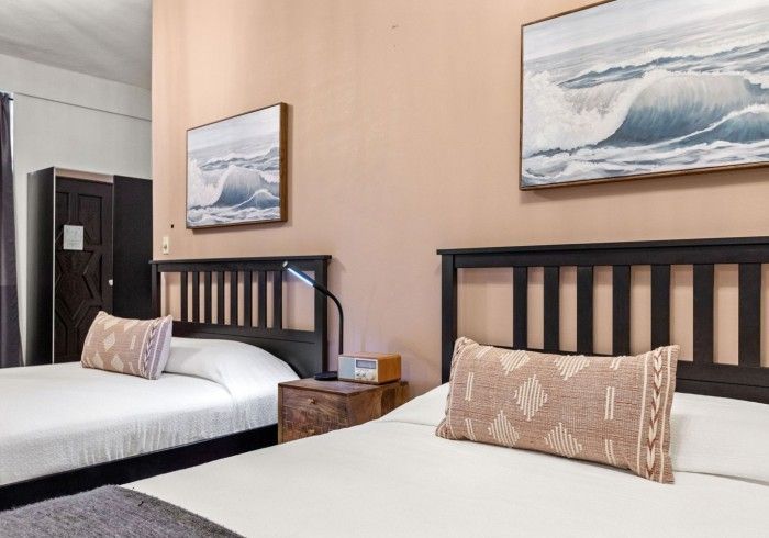 Two beds with brown headboards and patterned pillows in a bedroom.