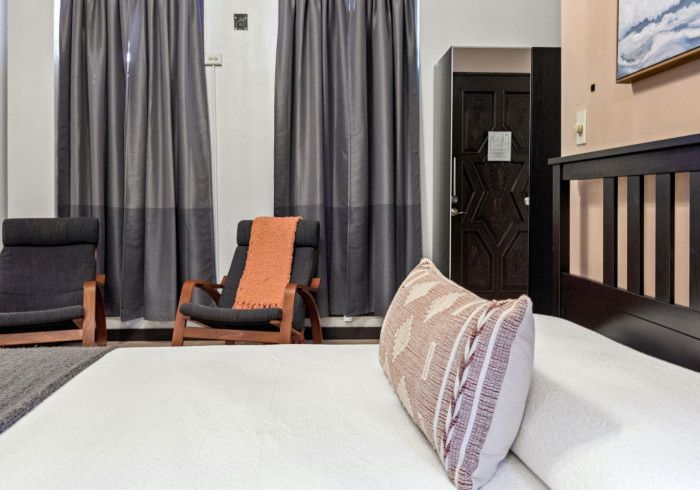 Bedroom with bed, chairs, and dark curtains. Pillow in focus.