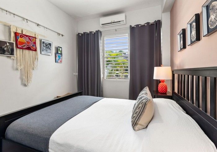 Bedroom with a bed, art, window, and dark curtains, featuring pink and white walls.