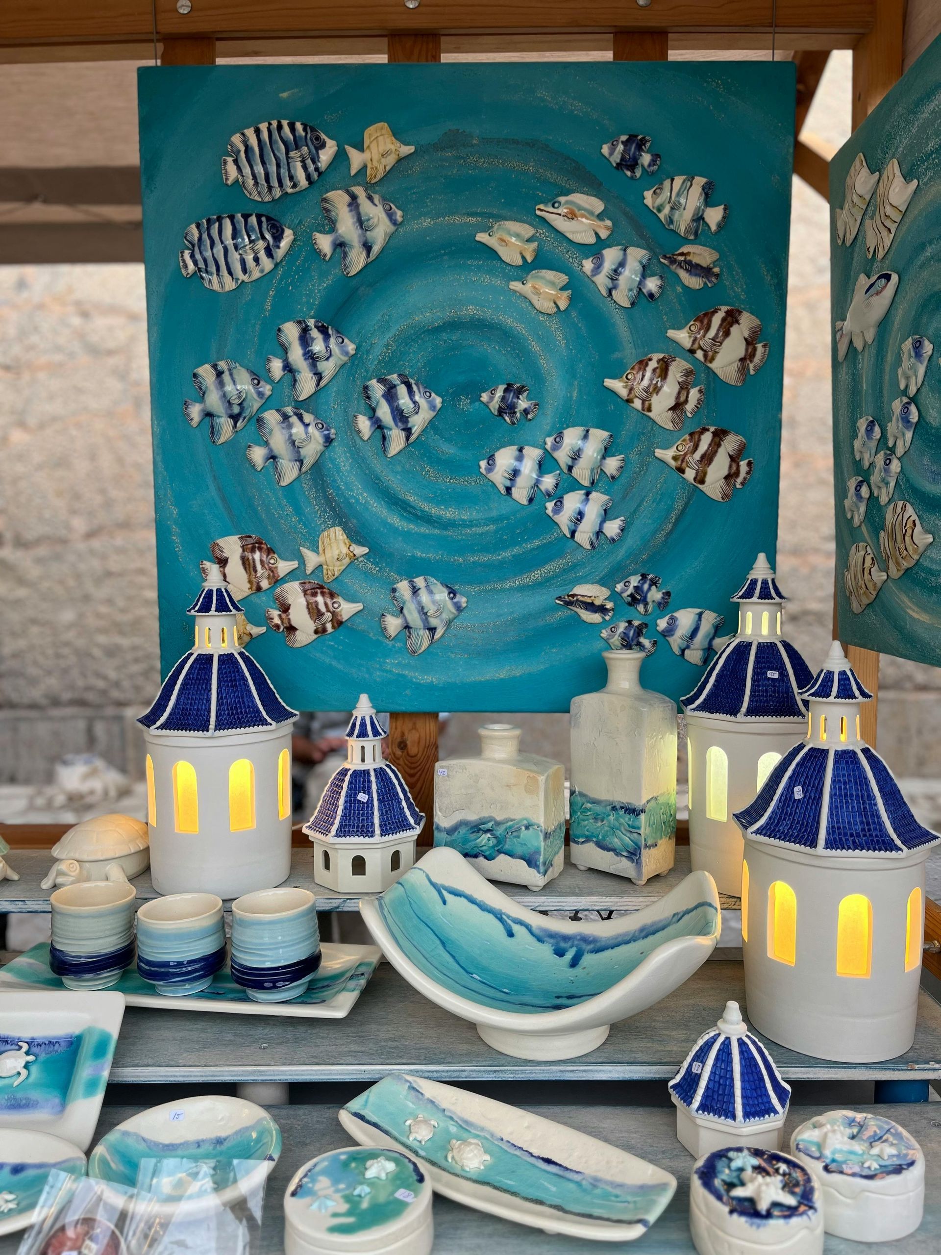 Ceramic art display: blue/white fish painting, lanterns, bowls, and cups. Ocean theme.