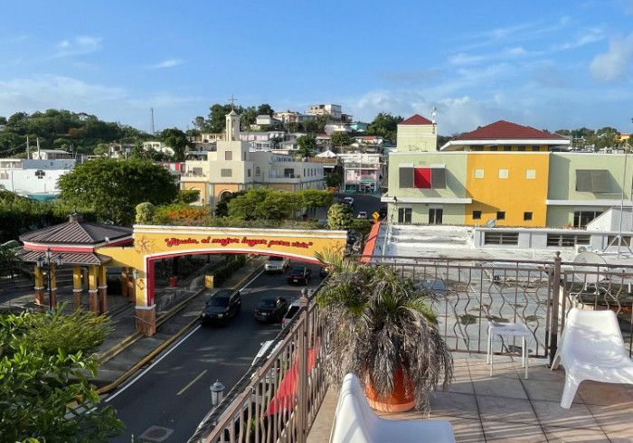 Town street with colorful buildings, blue sky, and an archway that reads 