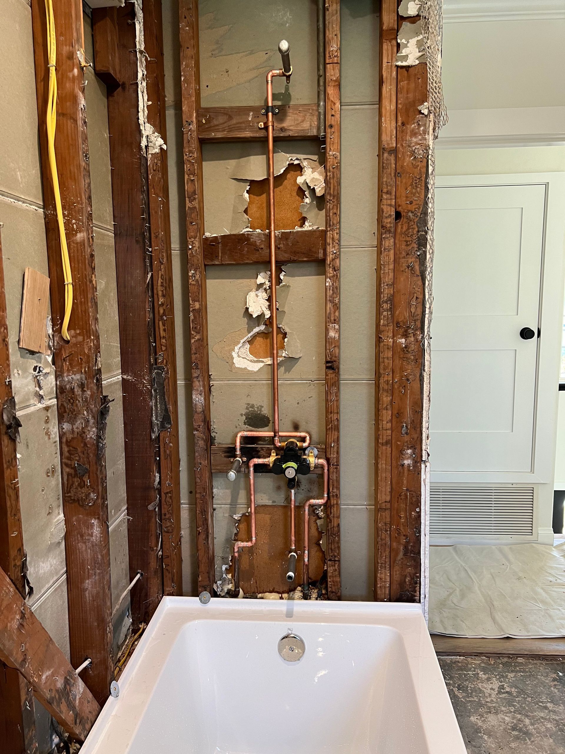 a bathtub in a bathroom under construction with copper pipes