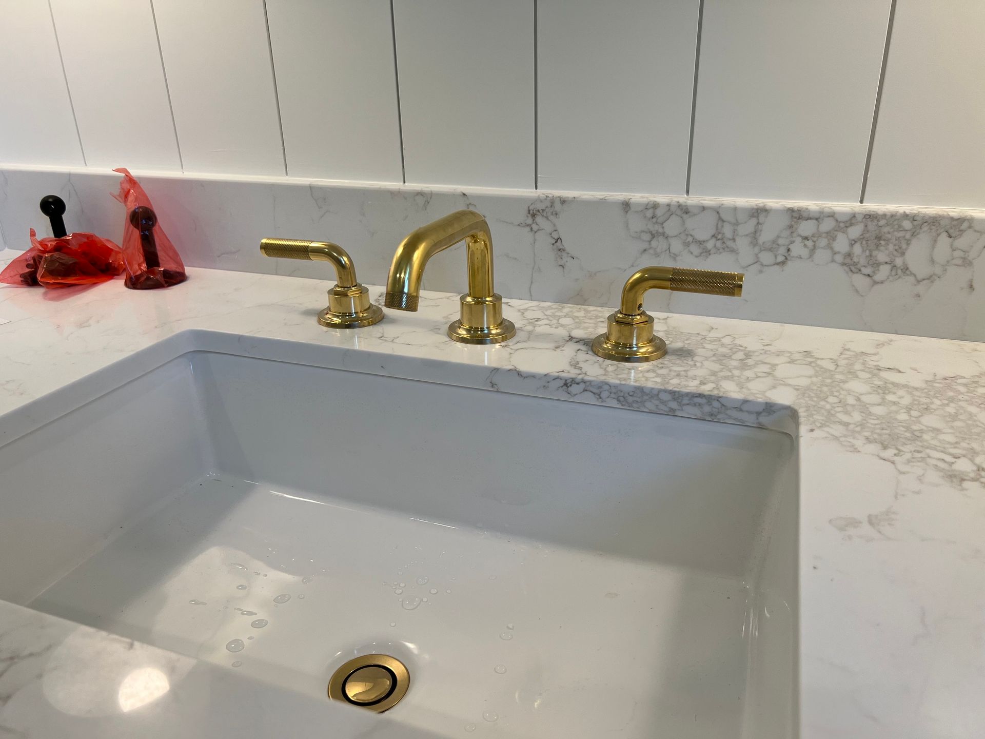 a bathroom sink with gold handles and a drain