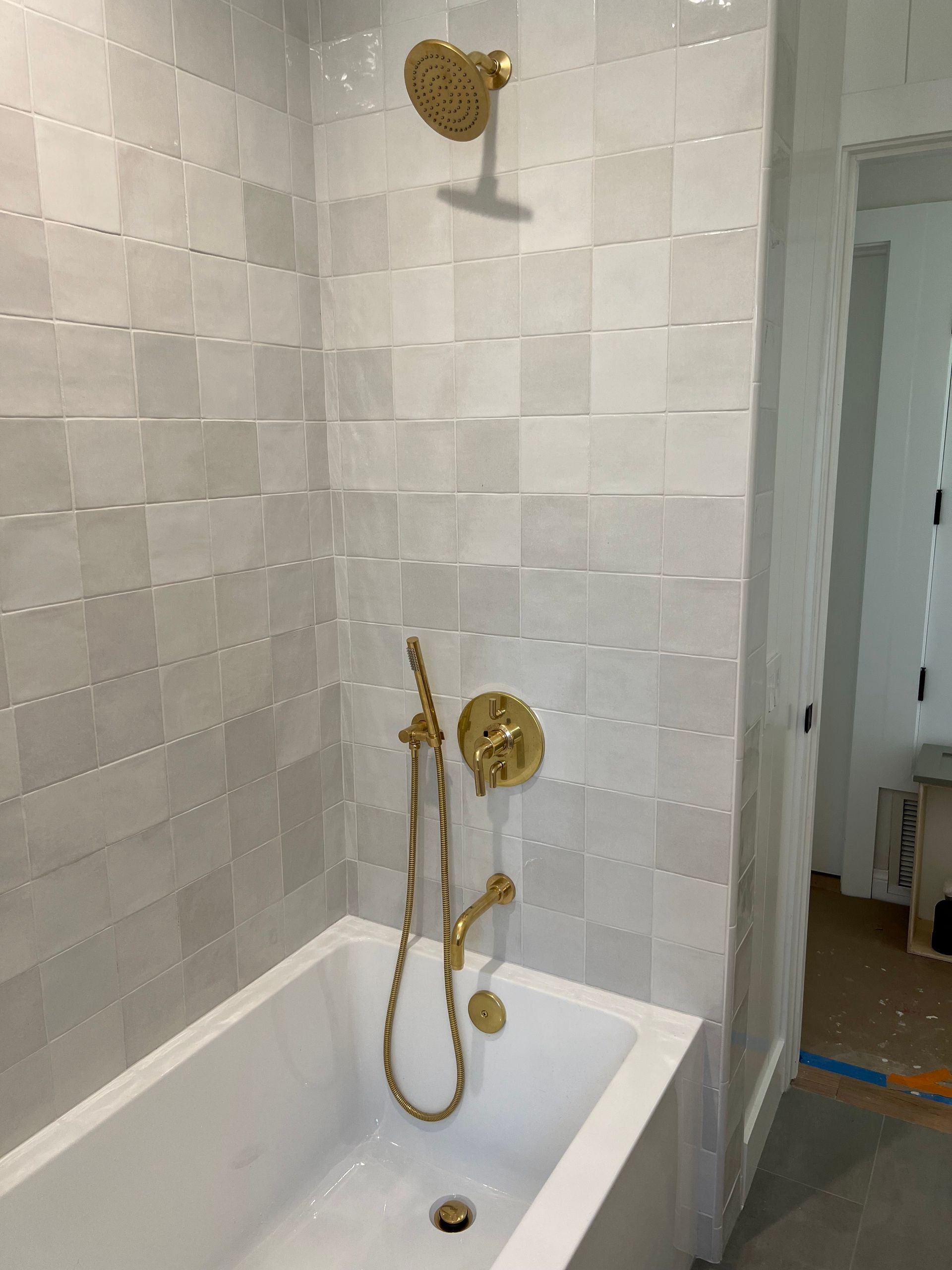 a bathroom with white tiles and a gold shower head