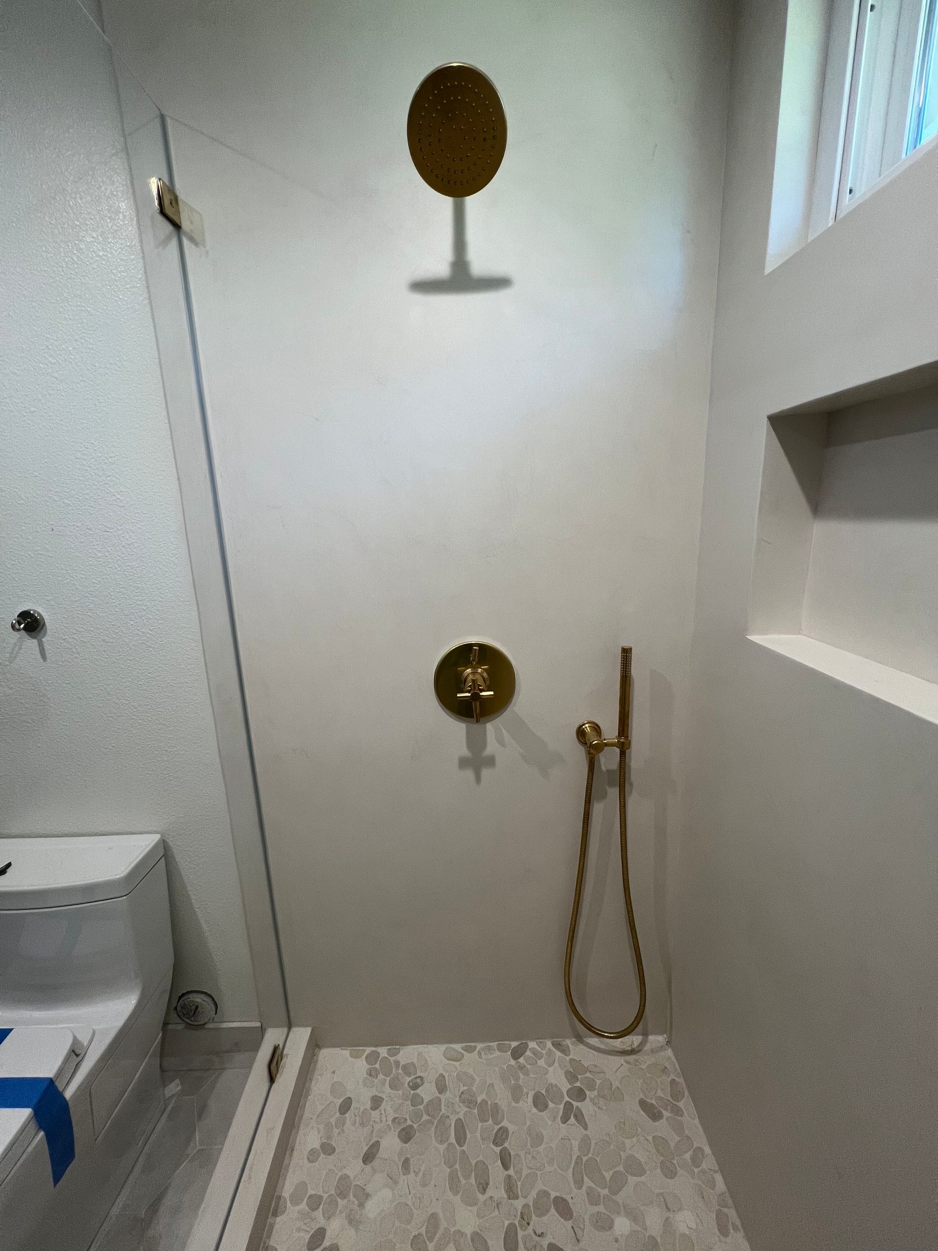 a bathroom with a toilet and a shower with a gold shower head