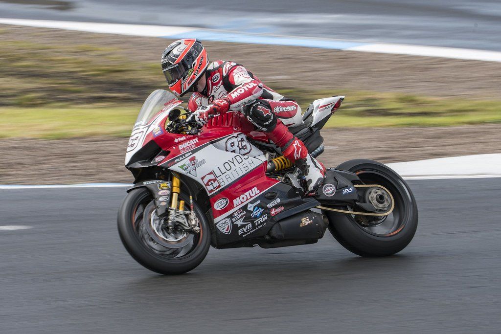 A man is riding a red and white motorcycle on a track