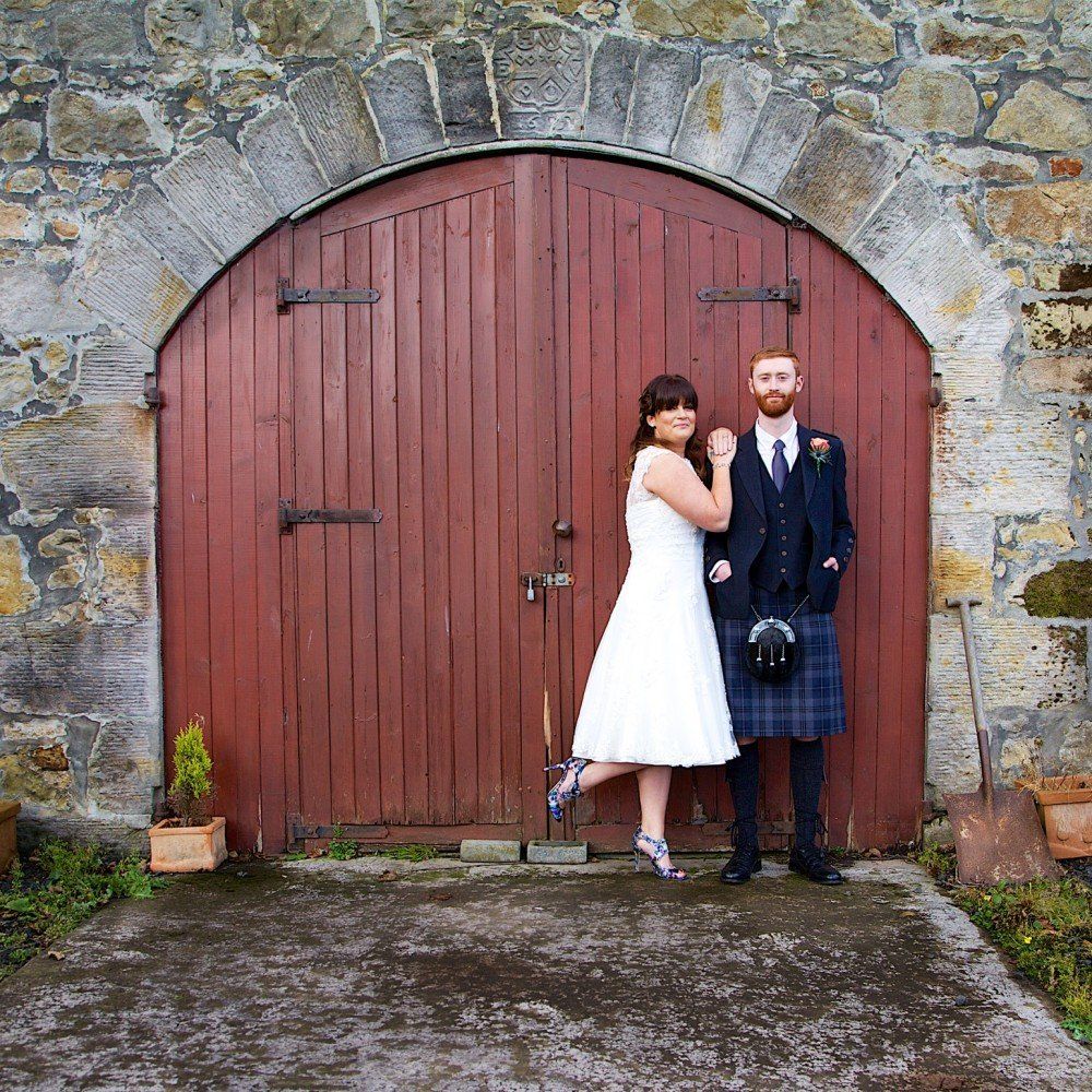 A bride and groom pose in front of a red door