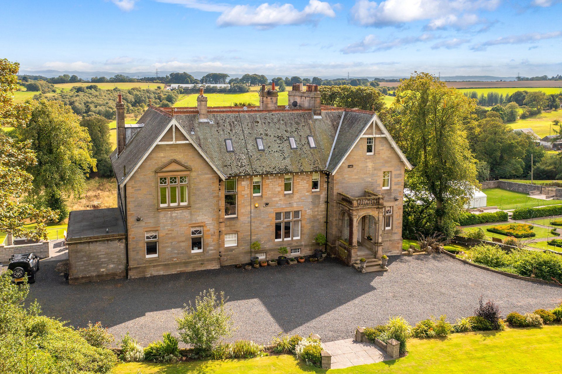 An aerial view of a large house surrounded by grass and trees