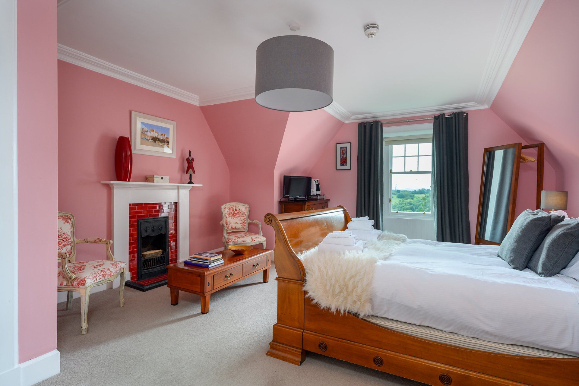 A bedroom with pink walls and a wooden bed