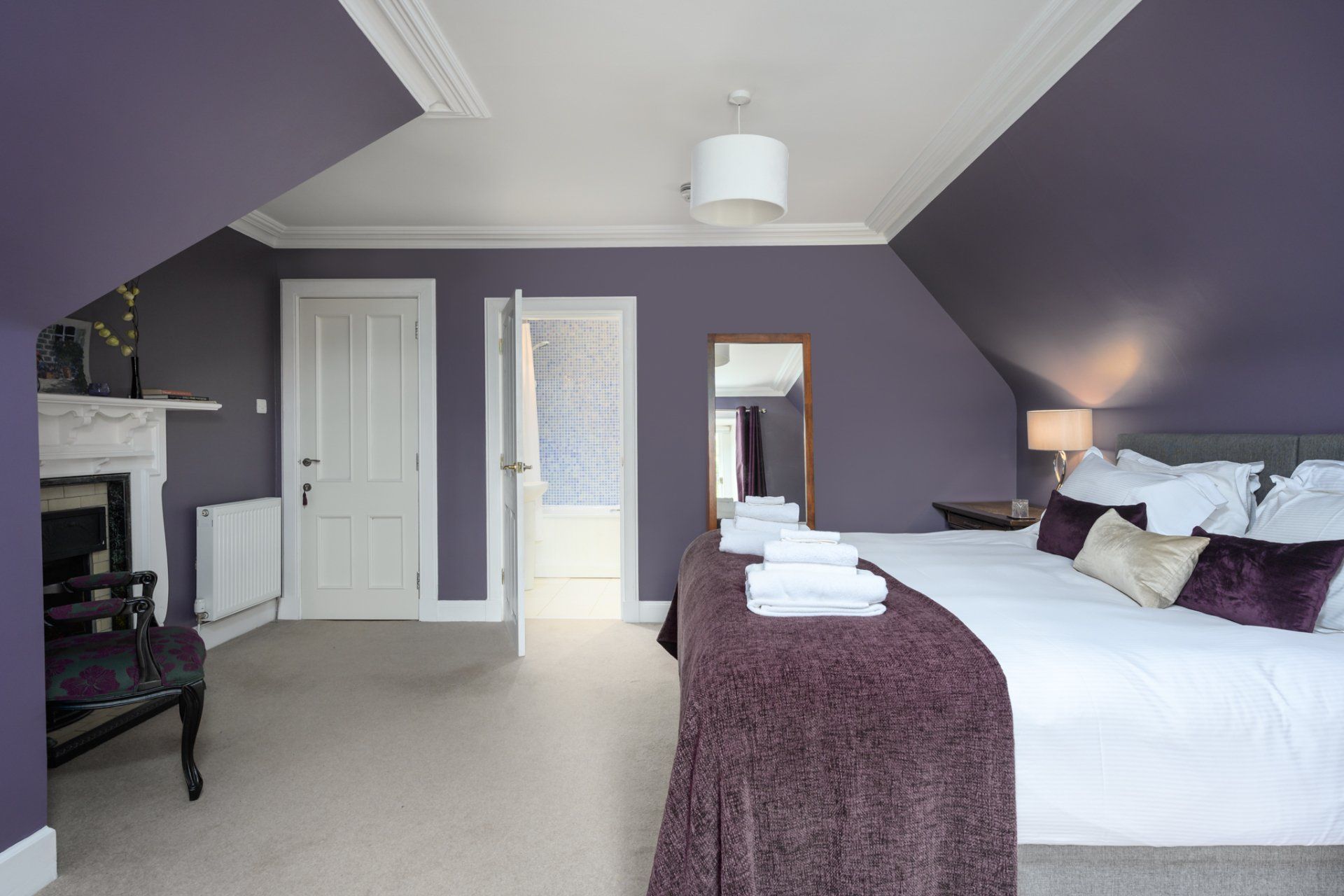 A bedroom with purple walls and a large bed