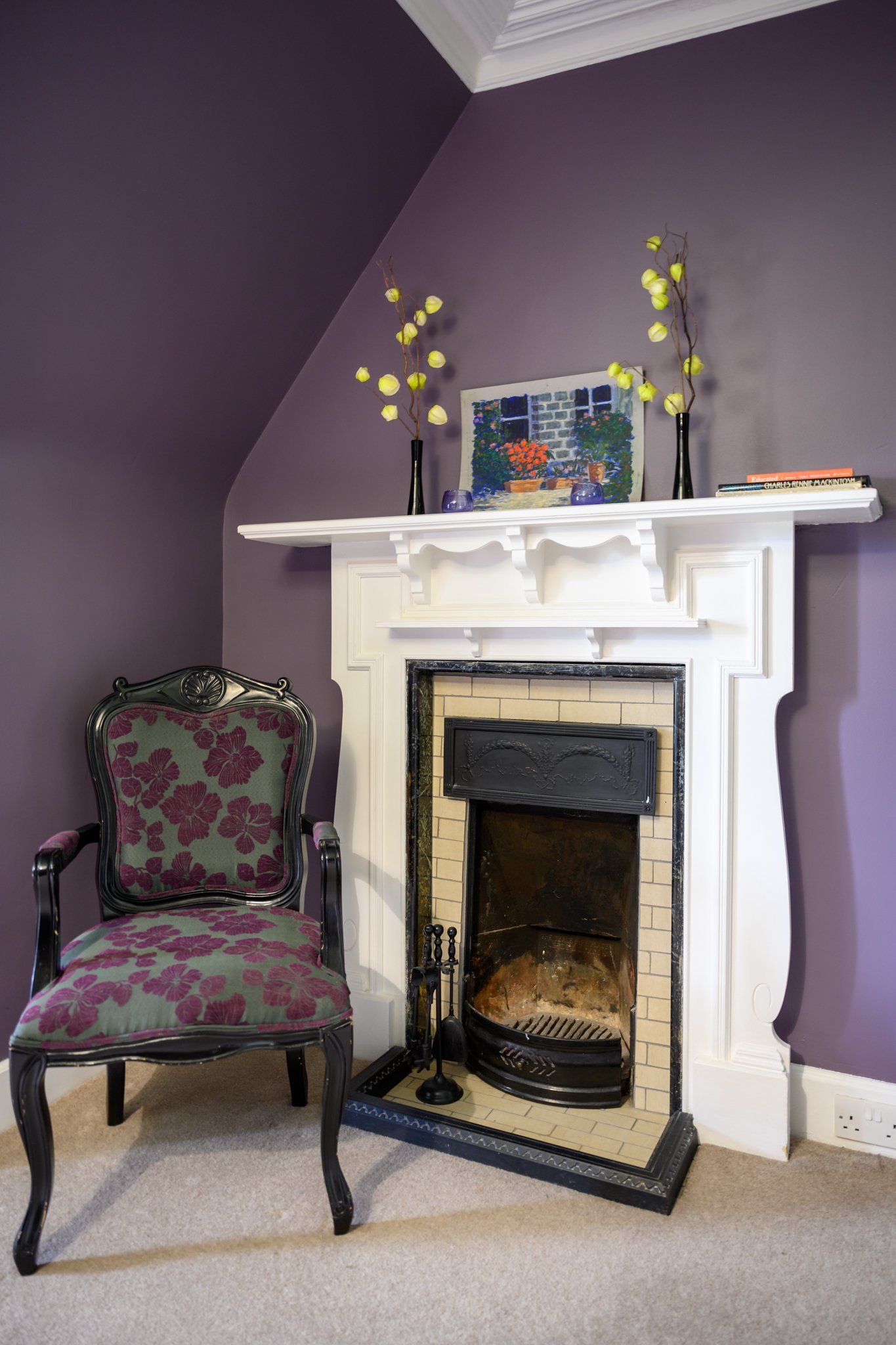 A chair sits in front of a fireplace with purple walls