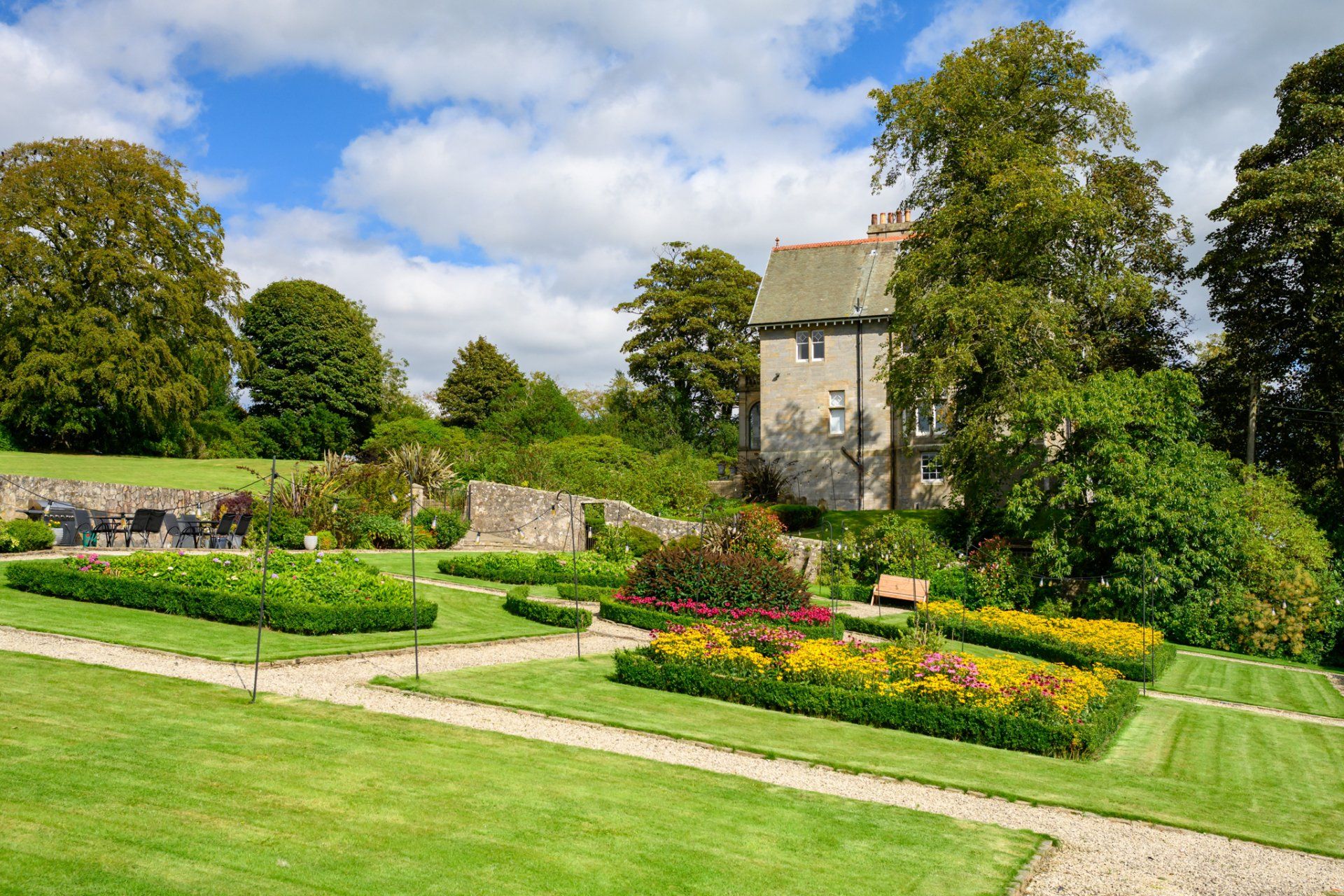 A garden with flowers and a house in the background