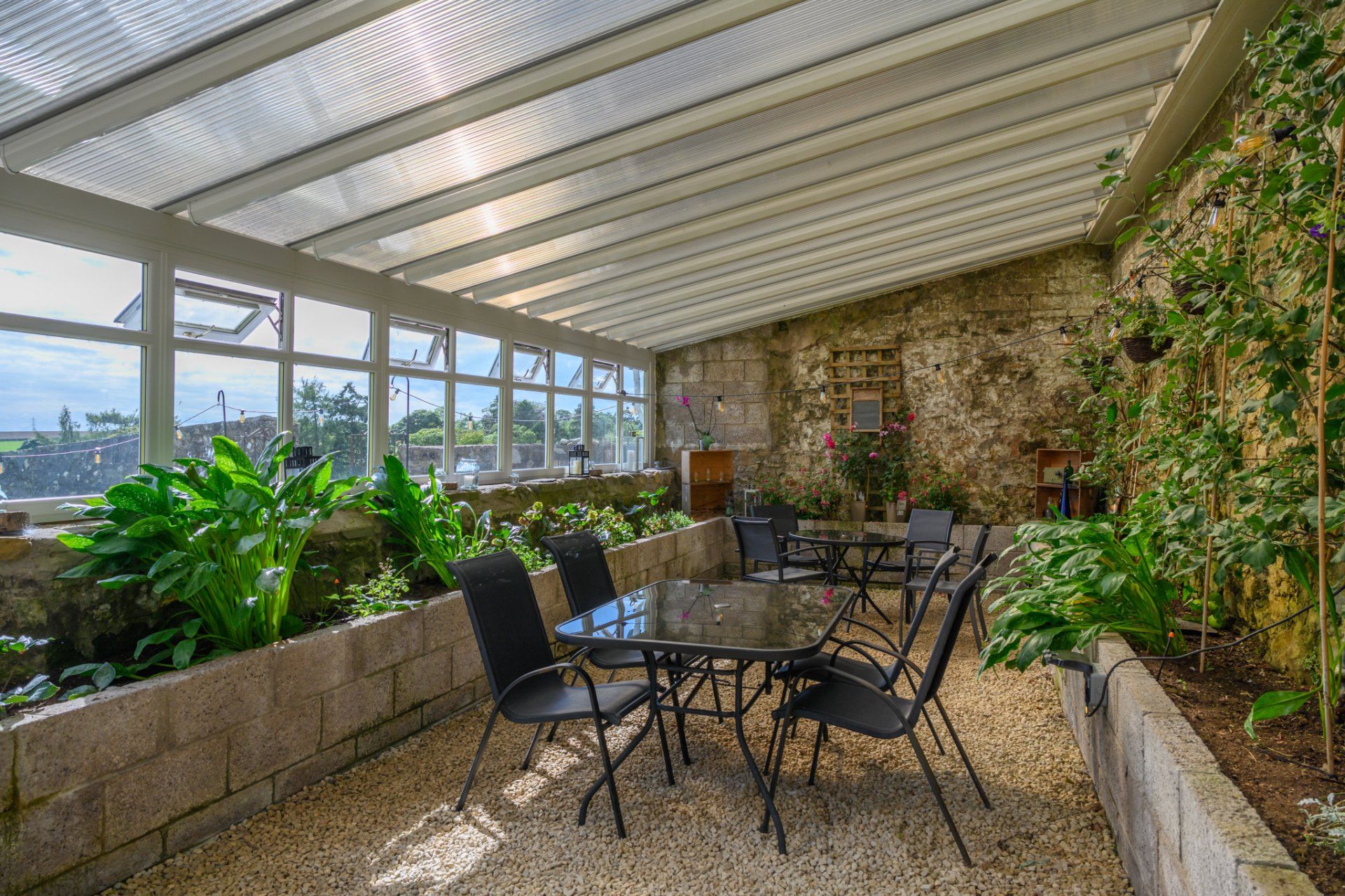 A patio with a table and chairs under a clear roof