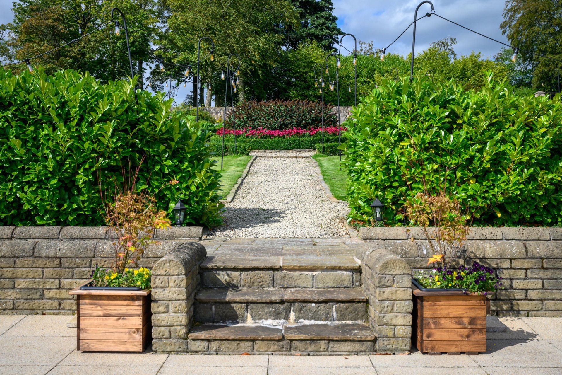 A stone walkway leading to a lush green garden