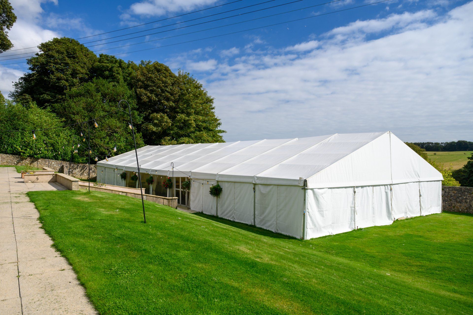 A large white tent is sitting in the middle of a lush green field