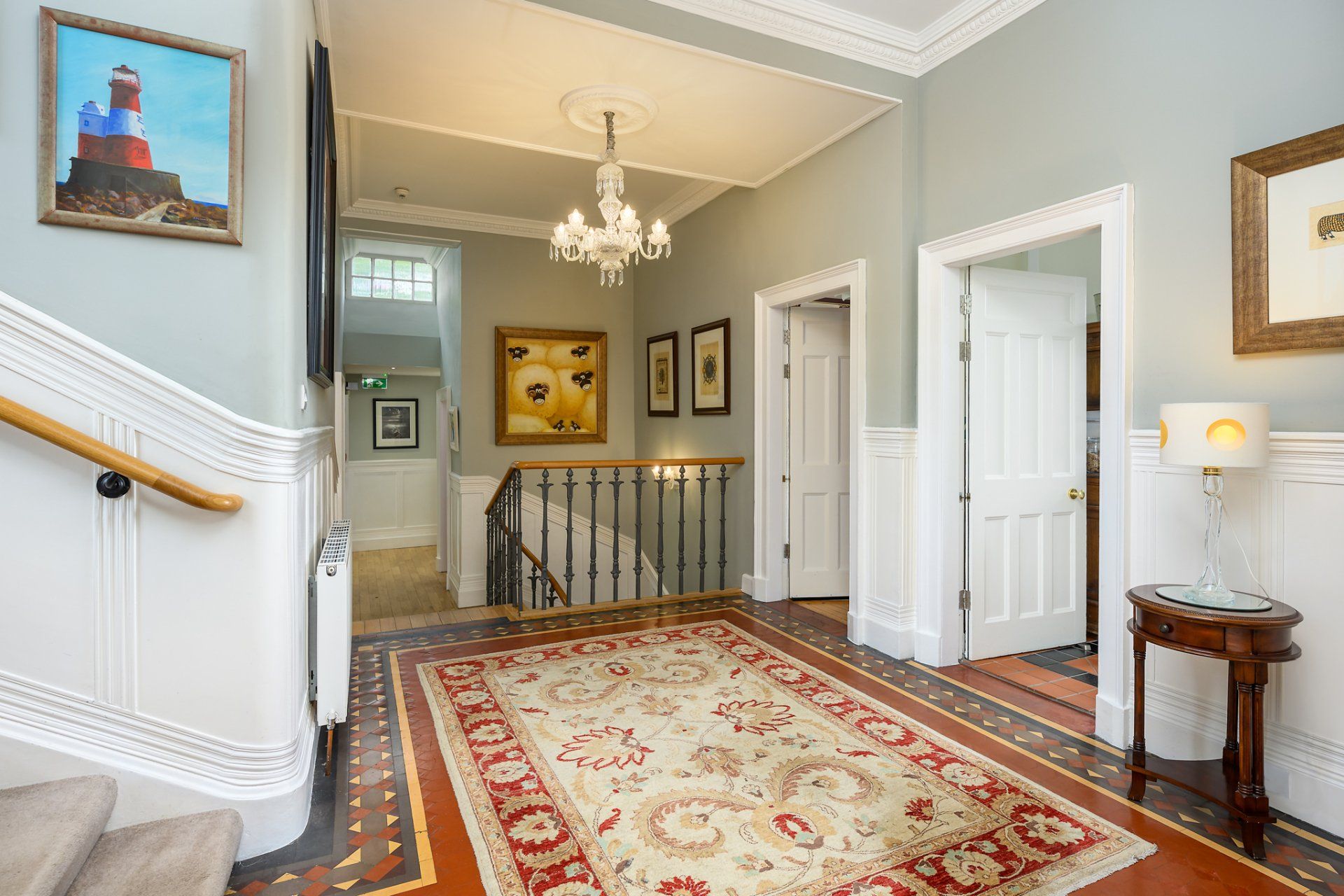A hallway with a rug and a picture of a lighthouse on the wall