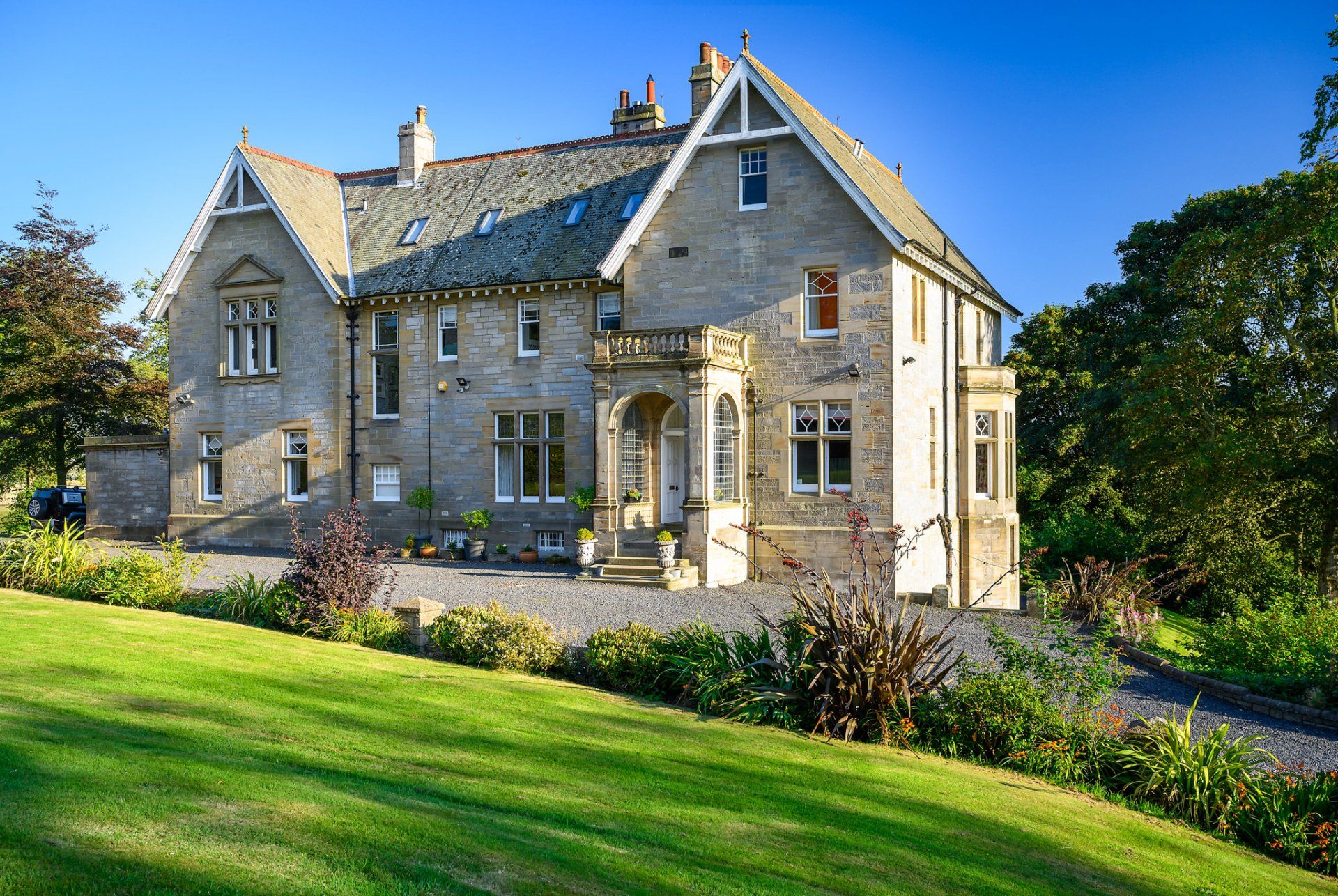 A large stone house sits on top of a lush green hillside