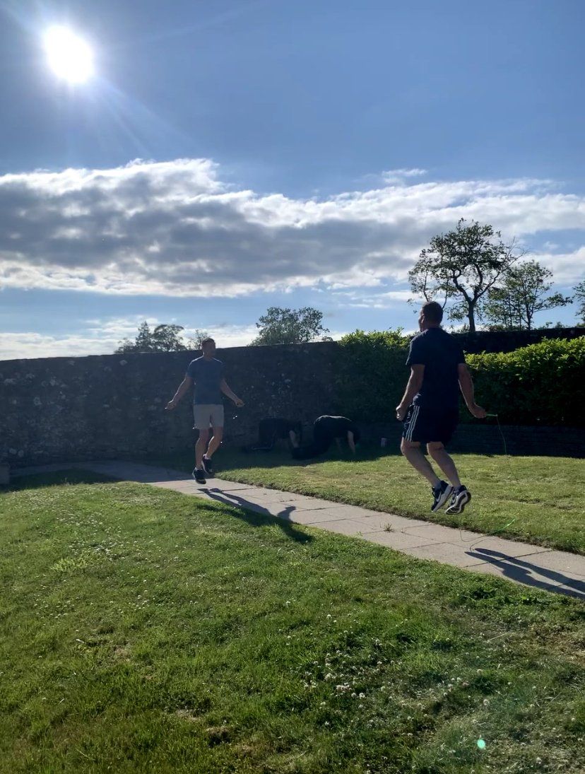 Two men are jumping rope in a park on a sunny day