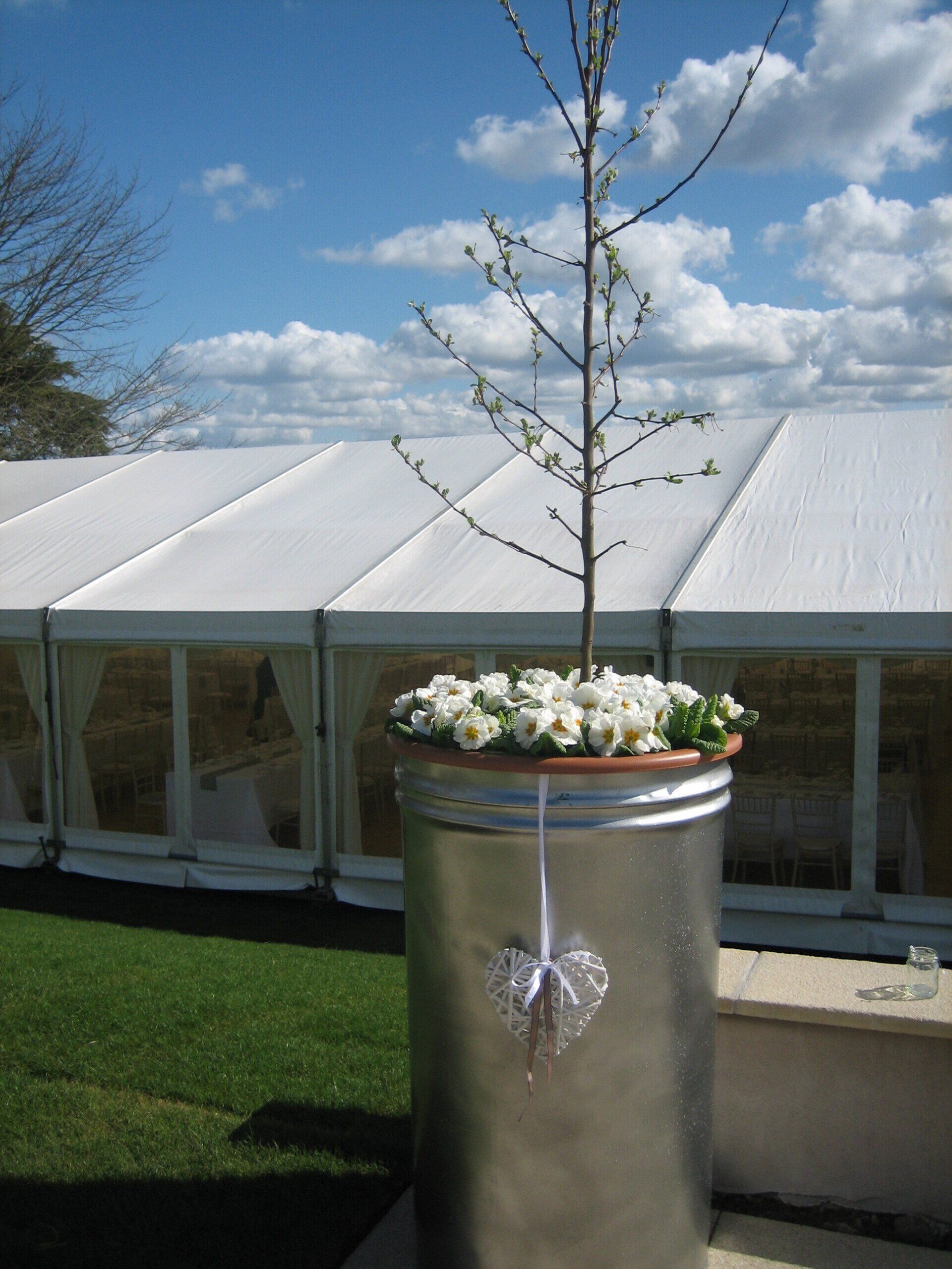 A metal planter with flowers and a heart hanging from it