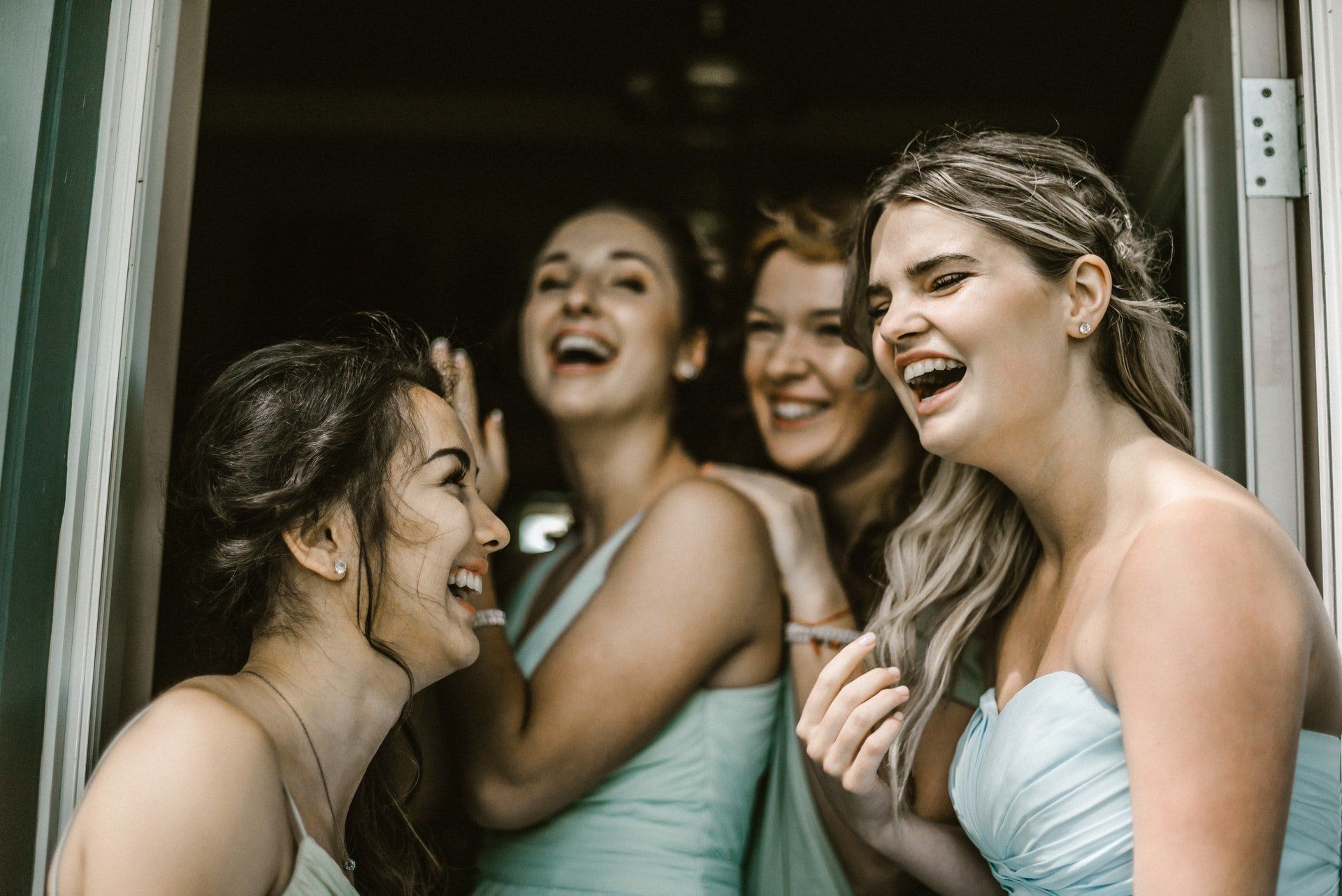 A group of women are laughing together in a doorway.