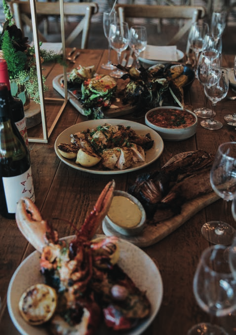 A wooden table topped with plates of food and a bottle of wine
