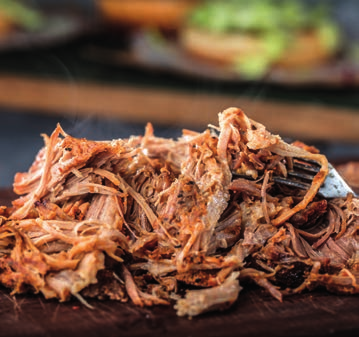 A pile of shredded meat with a fork on a cutting board.