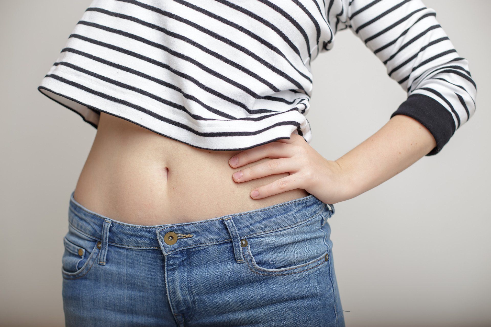 closeup of woman's midriff wearing striped shirt and jeans