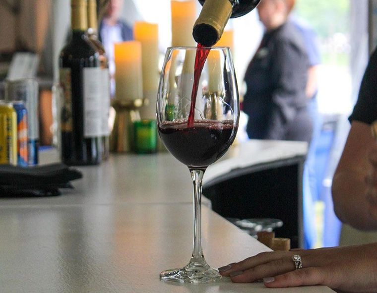 Wine being poured into a glass at a bar counter