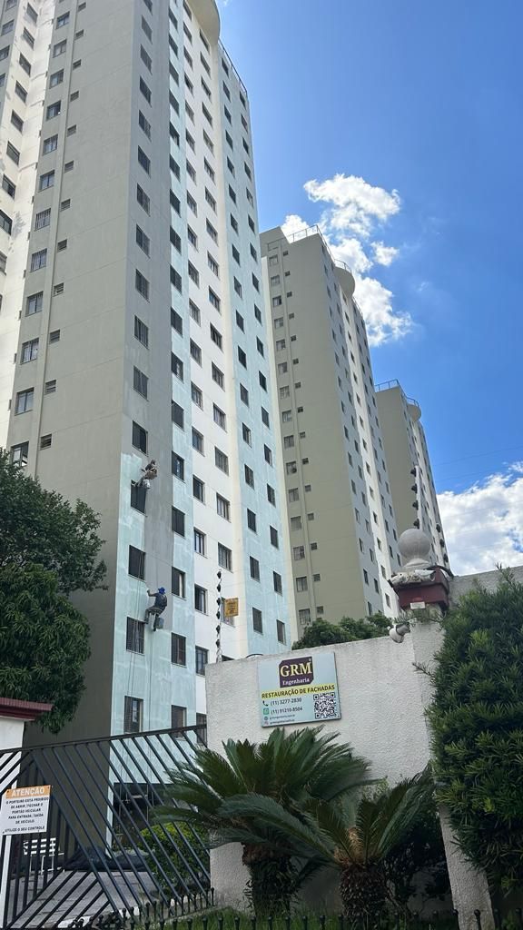 Um prédio alto com muitas janelas cercado por árvores e uma cerca.