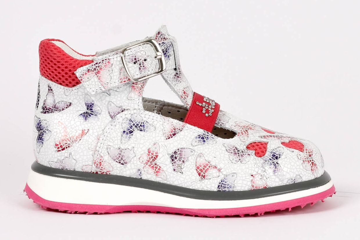 נעל ילדים לבנה עם הדפס אדום וכחול, נגיעות אדומות וסוליה ורודה, על רקע לבן.