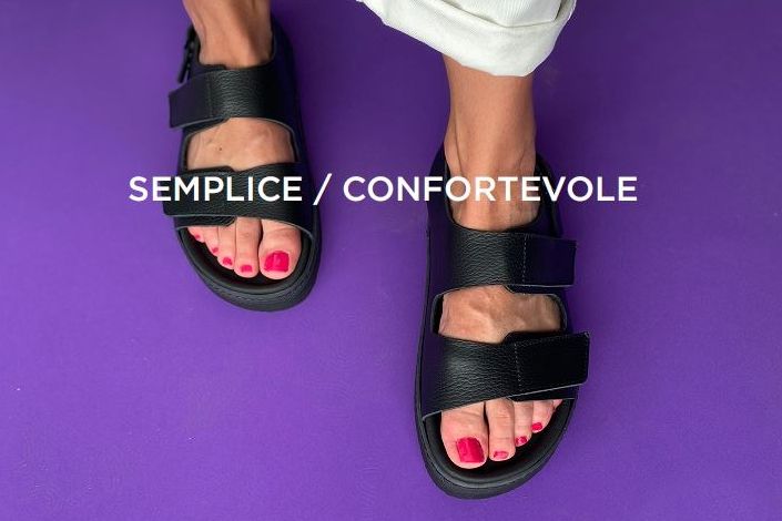 אדם נועל סנדלים שחורים עם לק אדום על רקע סגול.