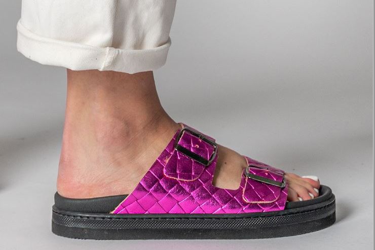 סנדלים מרופדים ורודים בוהקים על כף הרגל, בשילוב עם מכנסיים לבנים.